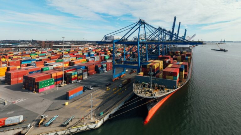 Terminal portuário com navio cargueiro atracado e contêineres empilhados durante operação de comércio exterior e logística internacional