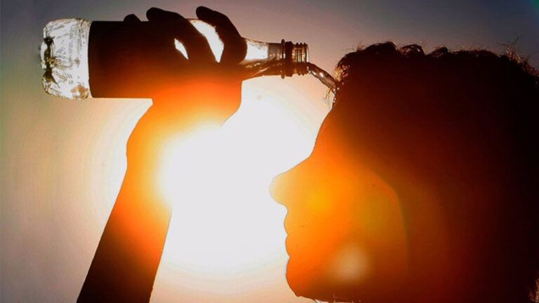 Pessoa bebe água de garrafa sob sol forte em cena que ilustra calor intenso e necessidade de hidratação