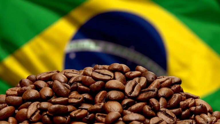 Grãos de café em destaque com bandeira do Brasil ao fundo em imagem sobre produção e exportação de café brasileiro