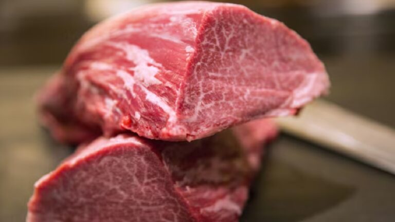 Corte de carne bovina crua com marmoreio visível apoiado em superfície de preparo para ilustração de matéria sobre consumo ou mercado de carnes