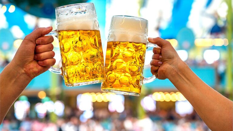 Canecas de cerveja brindam em festival ou bar em imagem sobre consumo de cerveja e bebidas alcoólicas