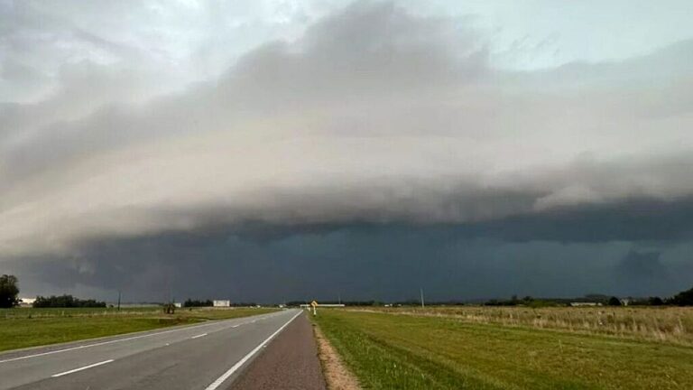 Nuvens densas de tempestade avançam sobre rodovia em área rural com céu escuro indicando mudança brusca no tempo