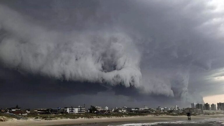 Nuvens densas avançam sobre cidade litorânea durante tempestade com formação de frente fria intensa